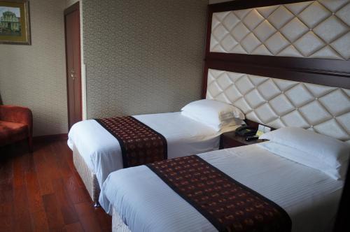 a hotel room with two beds and a chair at Seventh Heaven Hotel in Shanghai