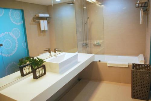 a bathroom with a white sink and a tub at Astoria Boracay in Boracay