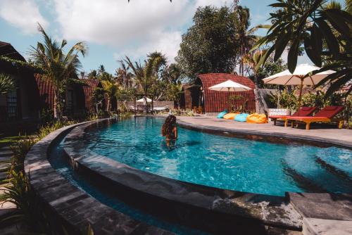 a woman standing in the water in a swimming pool at Papa Sun Villas in Nusa Penida