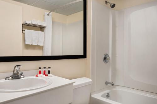 a bathroom with a sink and a toilet and a mirror at Super 8 by Wyndham Liverpool/Syracuse North Airport in Liverpool
