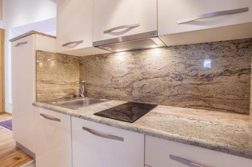 a kitchen with white cabinets and a sink at Apartments Calma in Cres