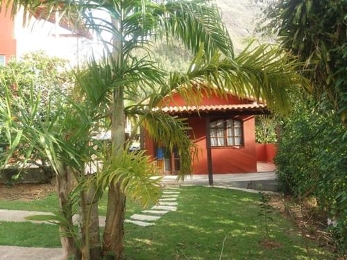 een klein rood huis met een palmboom ervoor bij Chales do Antonio in São Pedro da Serra