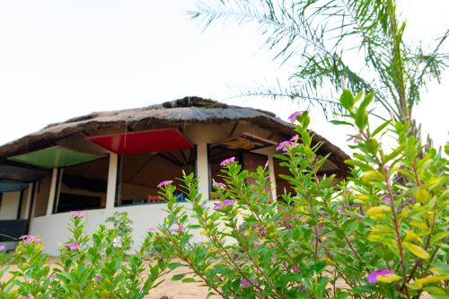 a house with a thatch roof and a colorful umbrella at Tamba Kuruba Eco-lodge in Folonko