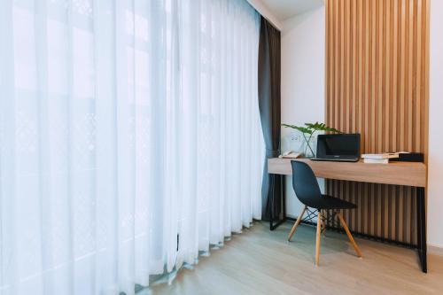 a desk with a computer and a chair next to a window at Nap in Chiangmai in Chiang Mai