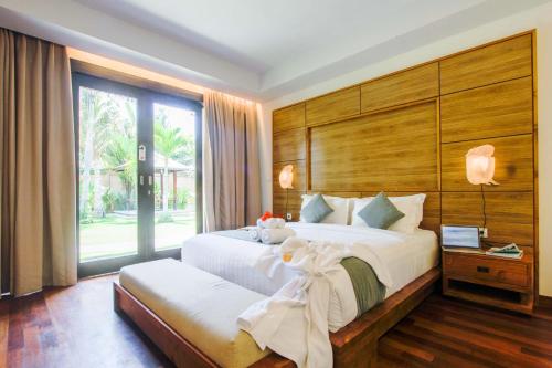 a bedroom with a large bed and a large window at djabu Canggu Beach Villa in Canggu