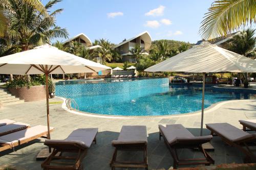 einen Pool mit Stühlen und Sonnenschirmen in einem Resort in der Unterkunft Sandunes Beach Resort & Spa in Mui Ne