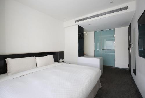 a bedroom with a large white bed and a bathroom at CityInn Hotel Plus - Taichung Station Branch in Taichung
