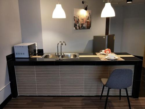 a kitchen with a sink and a counter with a chair at Popular Condo เมืองทองธานี in Pak Kret