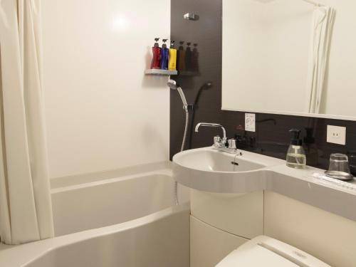 a white bathroom with a sink and a toilet at Candeo Hotels Ozu Kumamoto Airport in Ozu