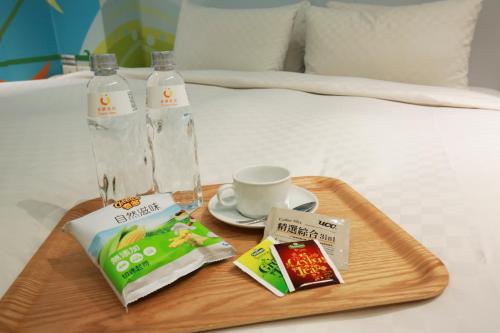 a tray of food on a bed with a bottle of water at CityInn Hotel Plus - Taichung Station Branch in Taichung