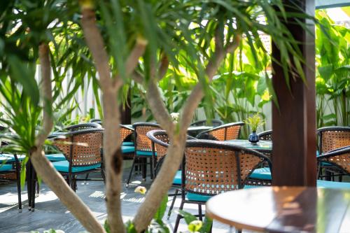 an outdoor patio with tables and chairs and trees at The Nam An Villa Hoi An in Hoi An