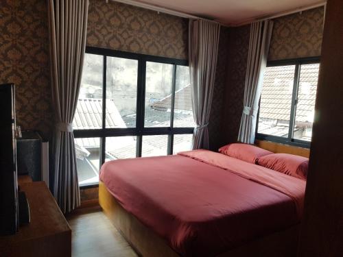 a bedroom with two beds and a large window at Tepbunthom Hostel in Bangkok