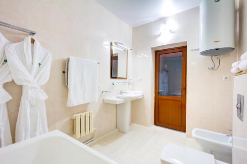 a white bathroom with a sink and a mirror at Navat Hotel in Bishkek