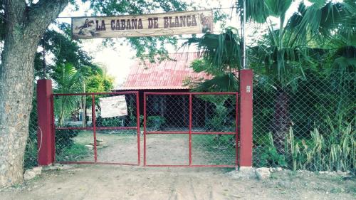a red gate with a sign in front of a tree at La Cabaña de Blanca in Jalpan