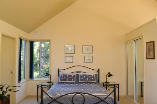 a bedroom with a bed and two windows at Bundle Hill Cottages in Bawley Point