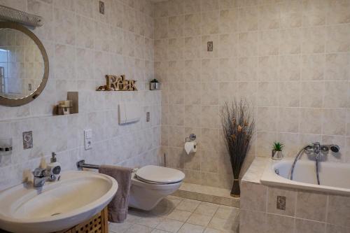 a bathroom with a sink and a toilet and a tub at Ferienapartment Christine in Simmerath