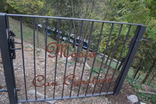 a gate with a sign that reads miracles on steroids at Masia Can Constans in Queralbs