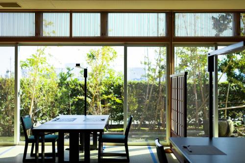 a dining room with a table and chairs and a large window at Migiwaya in Yaizu
