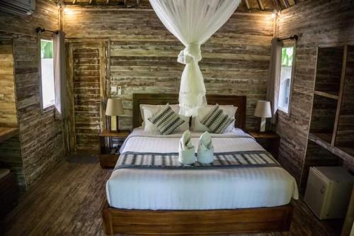 1 dormitorio con 1 cama blanca grande y paredes de madera en Green Garden Lembongan Yoga Spa and Holistic Healing Center, en Nusa Lembongan