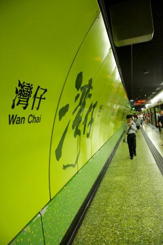 a woman walking down a subway tunnel with a sign on it at Kew Green Hotel Wanchai Hong Kong in Hong Kong