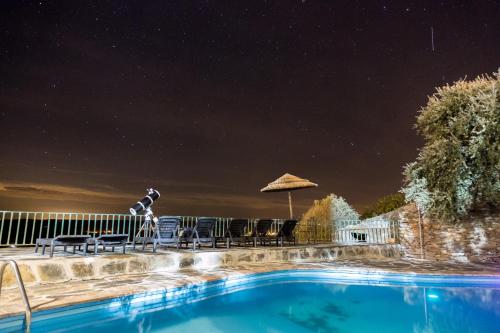 a pool with chairs and an umbrella at night at Estalagem de Monsaraz in Monsaraz