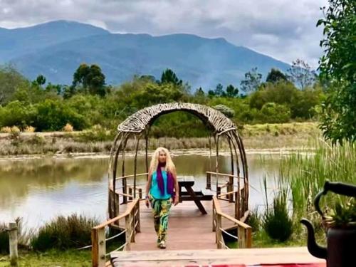 a woman walking across a bridge over a body of water at ECO Lodge Villa Villekula in The Crags