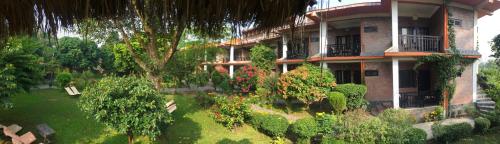 a building with a yard with bushes and trees at Chautari Garden Resort in Sauraha