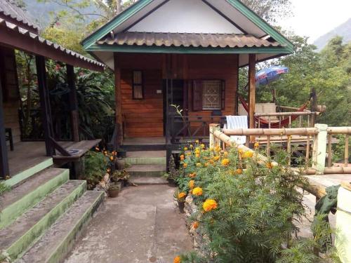 una pequeña cabaña con flores delante en SuanPhao Guesthouse en Muang Ngoy