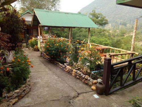 a garden with flowers in front of a house at SuanPhao Guesthouse in Muang Ngoy