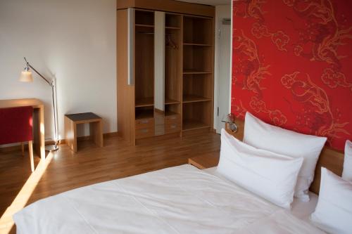 a bedroom with a white bed and a red wall at Gästehaus Auf dem Heiligen Berg B&B in Wuppertal