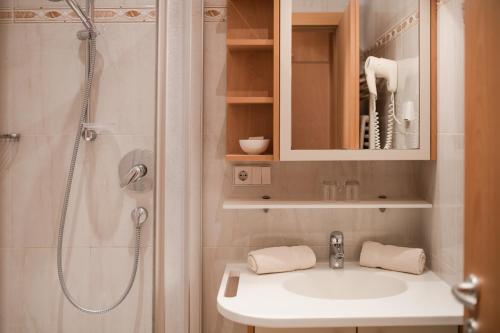 ein Badezimmer mit einem weißen Waschbecken und einer Dusche in der Unterkunft Pension Weingarten in Lana