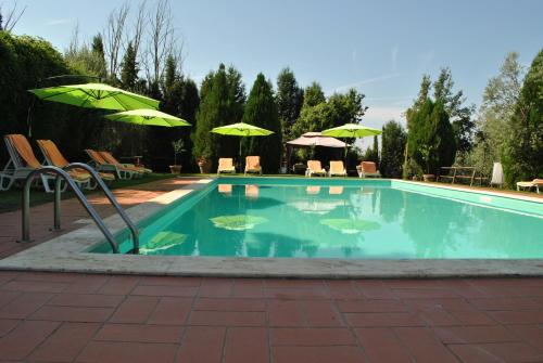 a swimming pool with green umbrellas and chairs at Agriturismo la Nicchia in Castelnuovo Berardenga