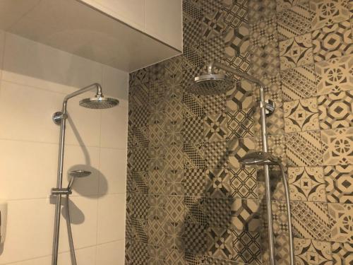 a shower in a bathroom with a tile wall at Hotel Hoevevoorde in Rijswijk