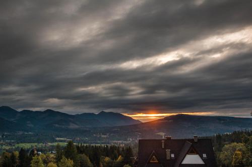 a cloudy sky over a house in the mountains at Noclegi u Gabrysi in Kościelisko