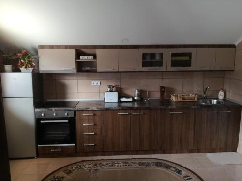 een keuken met houten kasten en een witte koelkast bij Apartman Vukan in Bajina Bašta