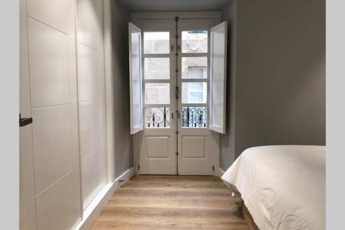 una camera da letto con un letto bianco e una finestra di Plaza Mayor a Ourense