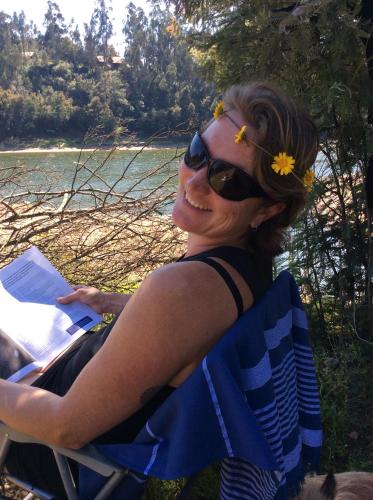 a woman sitting in a chair with a book at Unique Tiny House with Natural Building Techniques in Figueiró dos Vinhos
