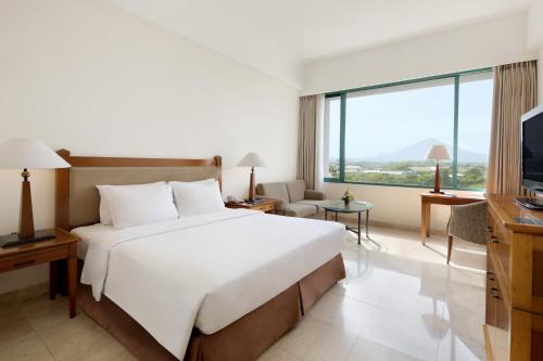 a hotel room with a bed and a television at Aryaduta Manado in Manado