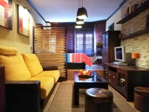 a living room with a yellow couch and a television at Apartamentos Arttyfal con parking y WiFi by SURYNIEVE in Sierra Nevada
