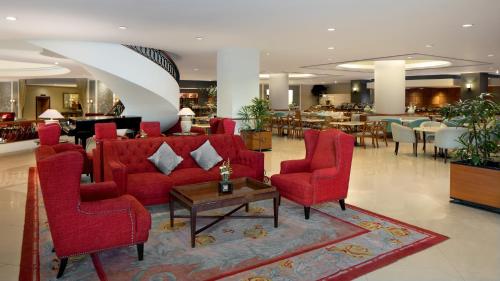 a lobby with red chairs and a table and a restaurant at Aryaduta Manado in Manado