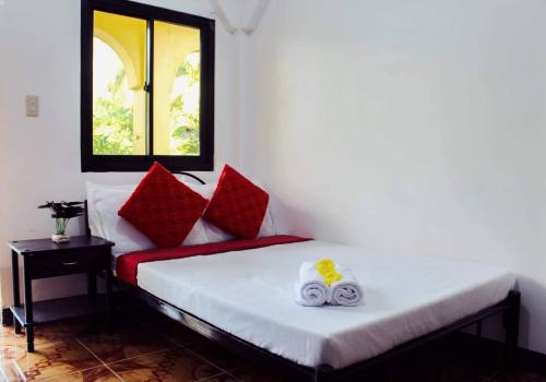 a room with a bed with red pillows and a window at Angel Gabriel Homestay in Coron