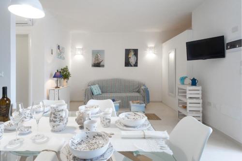 un soggiorno bianco con tavolo e sedie bianche di MILLEBOLLEBLU APARTMENTS a Lido Marini
