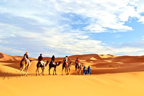 a group of people riding horses in the desert at Authentic riad & activities Erg in Mhamid