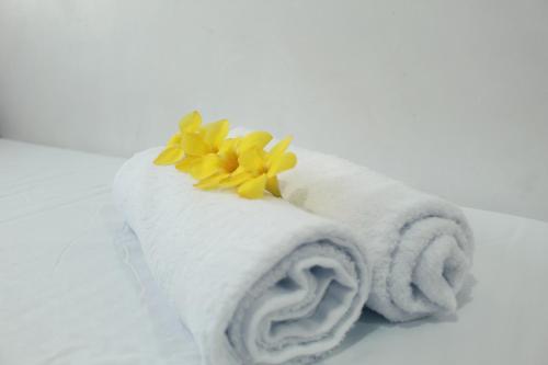 a white towel with a yellow flower on top of it at Angel Gabriel Homestay in Coron