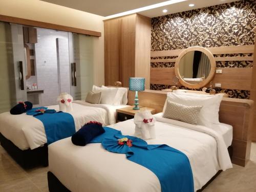 a hotel room with three beds and a mirror at Khaolak Blue Sky Villa in Khao Lak