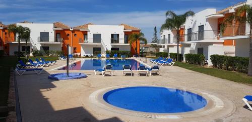 a swimming pool with lounge chairs and a resort at Jardins de Pera vila M in Pêra