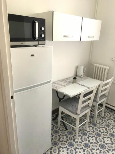 Il comprend une cuisine équipée d'un réfrigérateur blanc et d'une table avec des chaises. dans l'établissement Très bel appartement de style ancien avec sa terrasse en bois en coeur de ville, à Compiègne