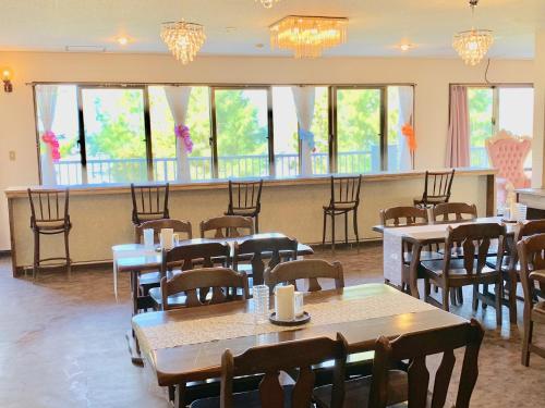a dining room with tables and chairs and windows at Hotel Hoshitate Iriomotejima in Iriomote