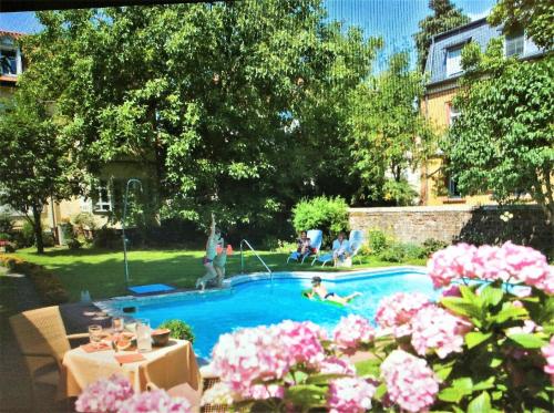 a person swimming in a swimming pool with pink flowers at Hotel-Pension Berger in Heidelberg