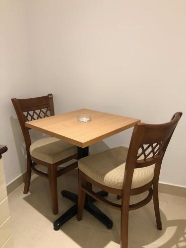a wooden table with two chairs and a table with a plate on it at Maxim Hotel in Cairo